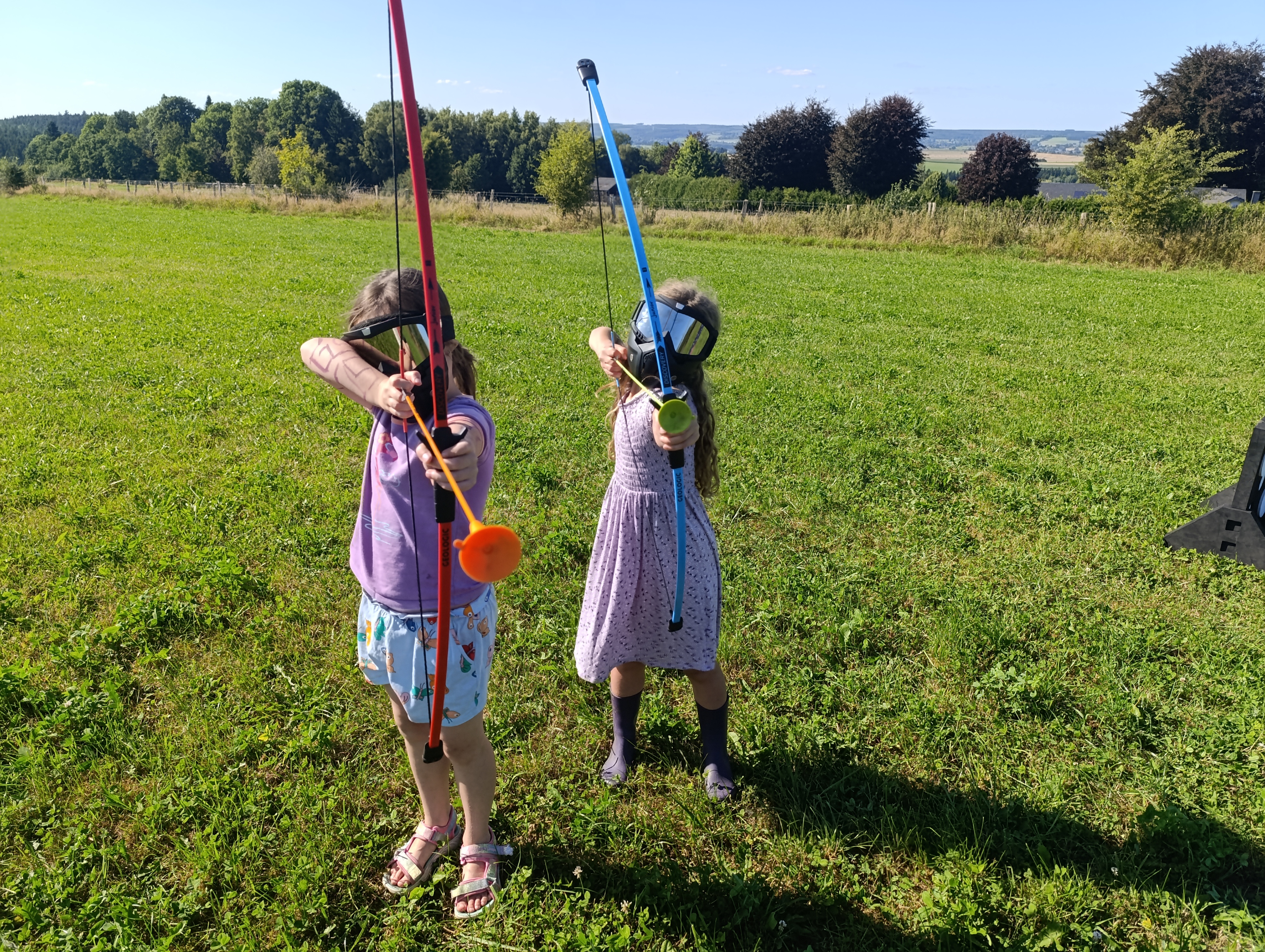 Photo de deux enfants équipées pour l'archery tag et visant avec leur arc
