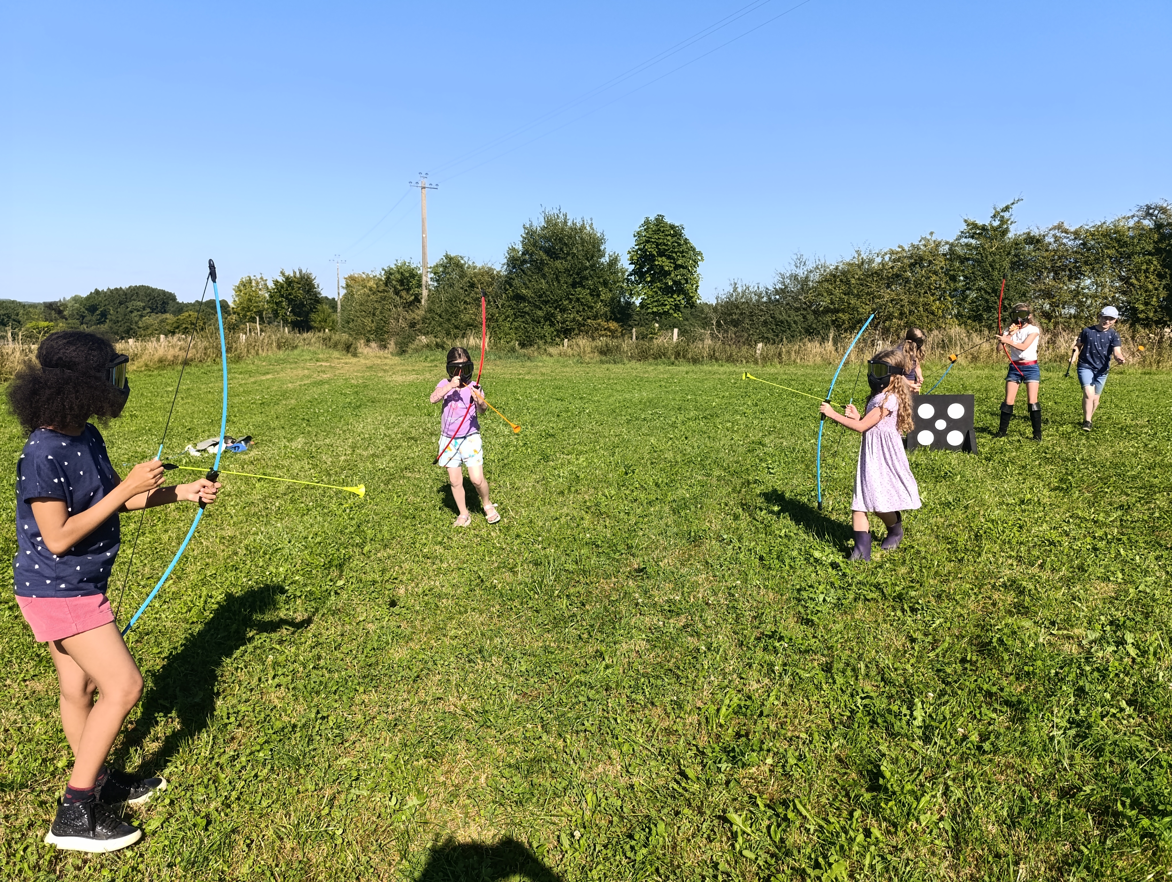 Photo de cinq enfants participant à un match d'archery tag dans une prairie