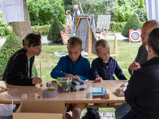 Photo d'enfants participant à un atelier de création d'arbalète avec leurs parents
