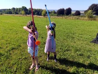 Photo de deux enfants équipées pour l'archery tag et visant avec leur arc