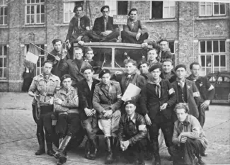 Photo d'archive d'un groupe de résistants posant fièrement autour d'une voiture criblée de balles.