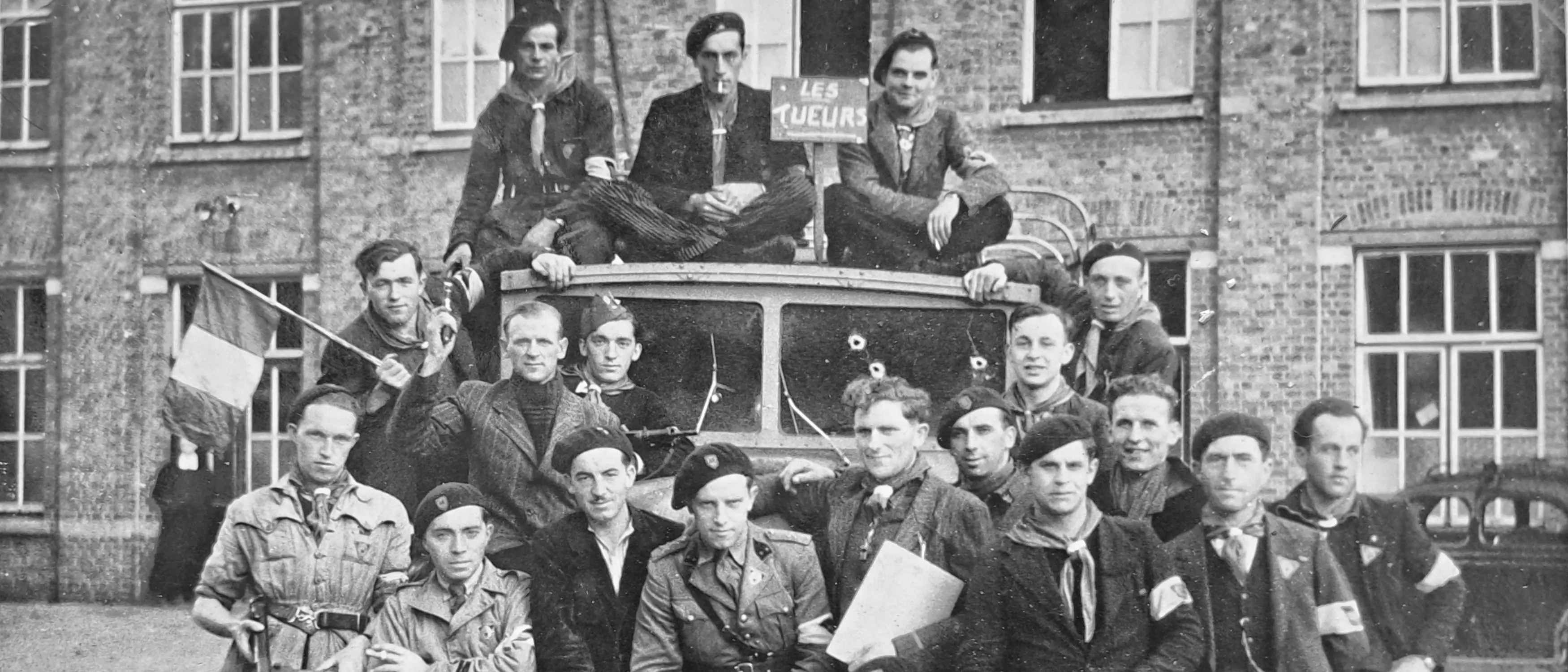 Photo d'archive d'un groupe de résistants posant fièrement autour d'une voiture criblée de balles.